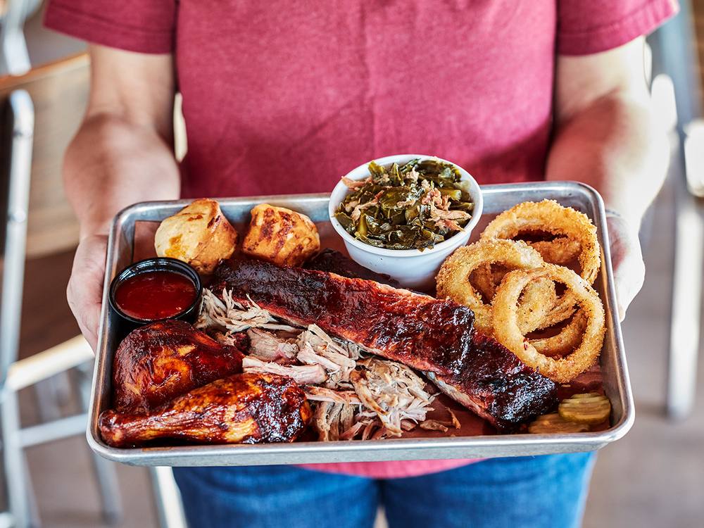 Tray of slow-smoked barbecue with onion rings and sauce